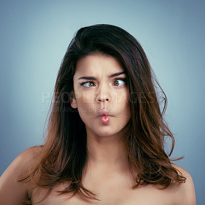 Buy stock photo Studio shot of a beautiful young woman making a silly face against a blue background
