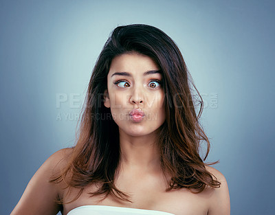 Buy stock photo Studio shot of a beautiful young woman making a silly face against a blue background