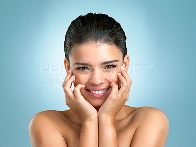 Buy stock photo Studio shot of a gorgeous young woman holding her cheeks against a blue background