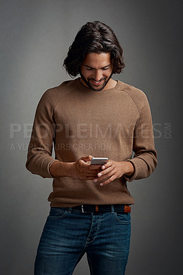 Buy stock photo Happy man, cellphone and reading in studio for notification, ebook and online or mobile app. Smile, male model and social media or internet for networking, communication and typing by dark background