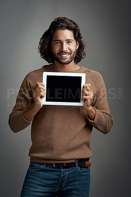 Buy stock photo Studio shot of a handsome young man holding a digital tablet with a blank screen against a gray background
