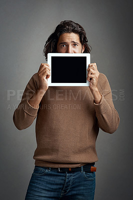 Buy stock photo Tablet screen, mockup and portrait of man peeking in studio isolated on a gray background. Touchscreen, scared and male person with space for marketing, advertising and technology for promotion.