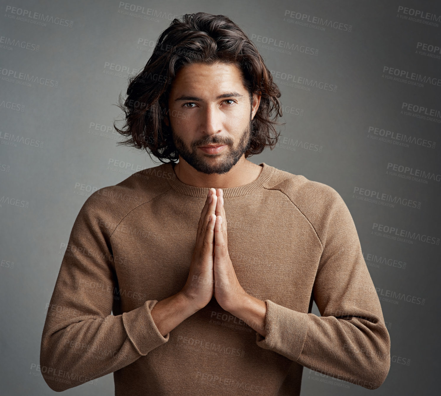 Buy stock photo Studio shot of a handsome young man praying against a gray background