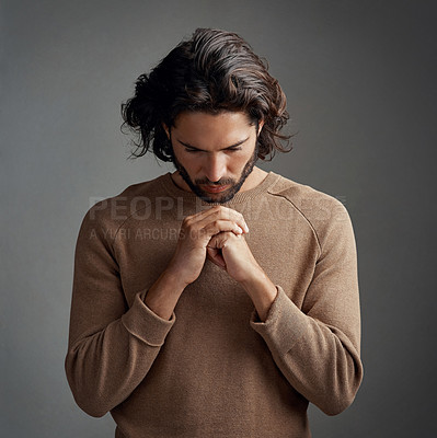 Buy stock photo Studio shot of a handsome young man praying against a gray background