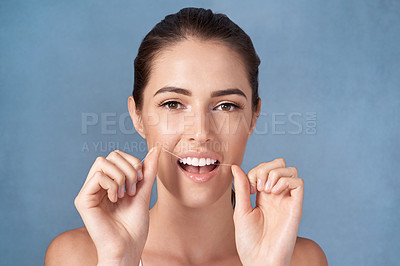 Buy stock photo Studio portrait of an attractive young woman flossing her teeth against a grey background