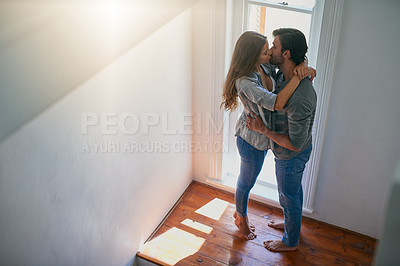 Buy stock photo Shot of an affectionate young couple sharing a kiss at home