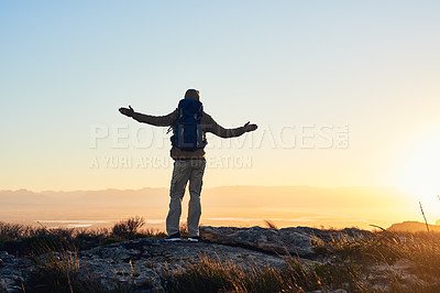 Buy stock photo Shot of a hiker with his arms raised standing on top of a mountain