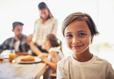 Buy stock photo Portrait of a little boy having breakfast with his family in the background