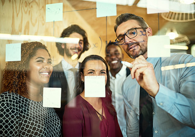 Buy stock photo Cropped shot of coworkers using sticky notes on a glass wall during a meeting in the office