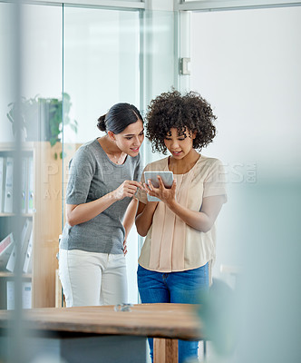 Buy stock photo Shot of two office colleagues having a discussion over a digital tablet