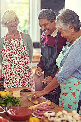 Buy stock photo Shot of a group of mature friends cooking at home