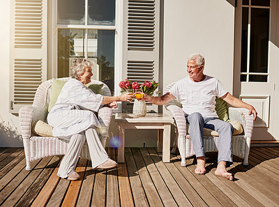 Buy stock photo Shot of a happy senior couple toasting with juice on the patio at home