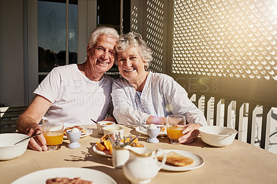 Buy stock photo Shot of a happy senior couple having a leisurely breakfast on the patio at home