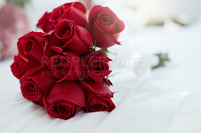 Buy stock photo Shot of a bunch of red roses lying on a bed