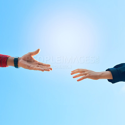 Buy stock photo Shot of two unidentifiable hikers reaching for each other's hands against a clear blue sky