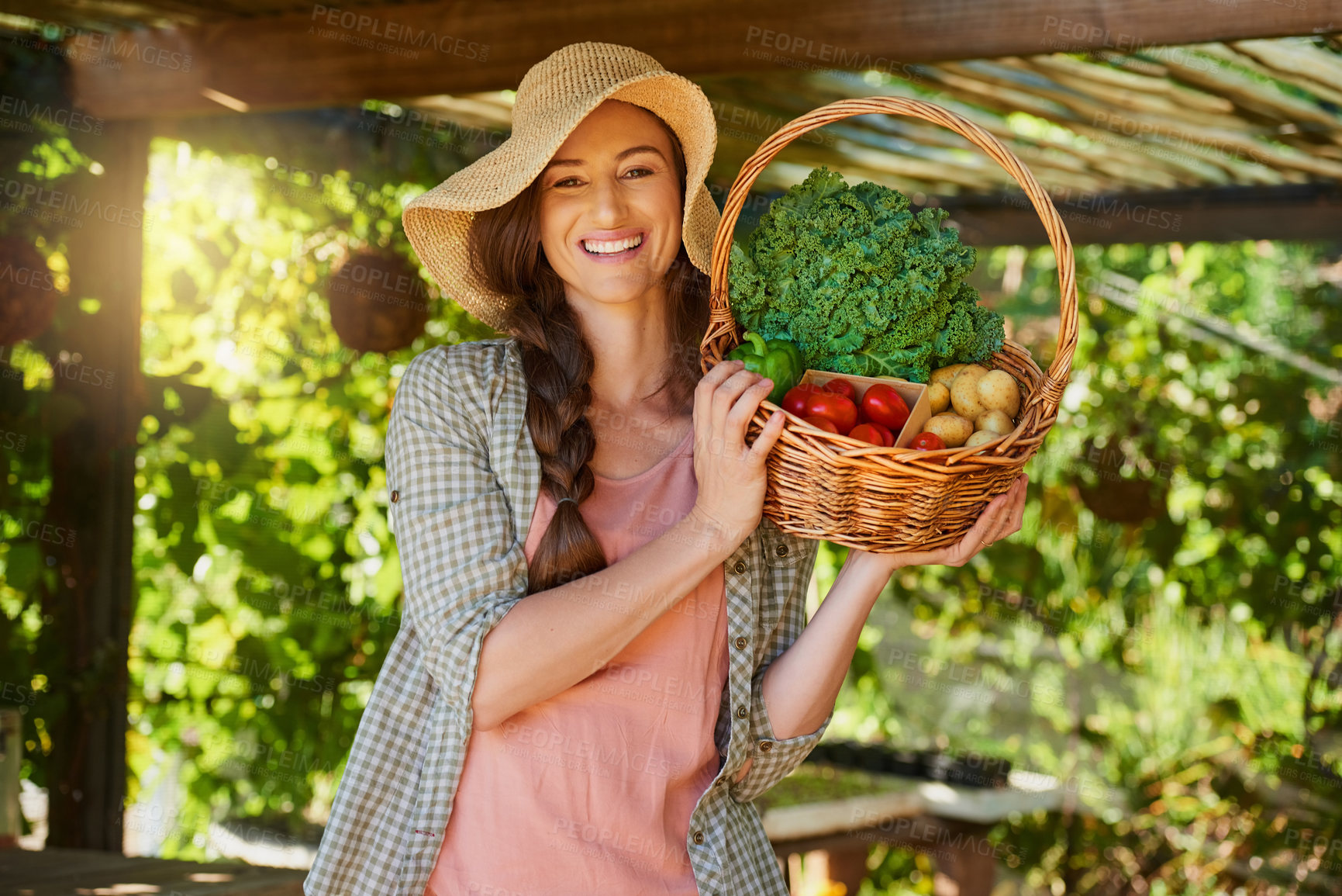 Buy stock photo Portrait of a young woman carrying a basket of freshly picked produce in a garden