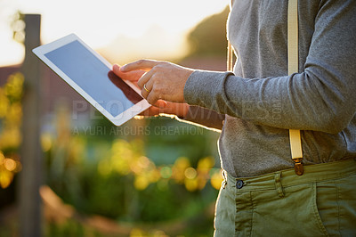 Buy stock photo Cropped shot of a man using a digital tablet while working in the garden