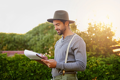 Buy stock photo Shot of a young man checking the stock in his garden