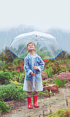Buy stock photo Full length shot of a young boy standing outside in the rain