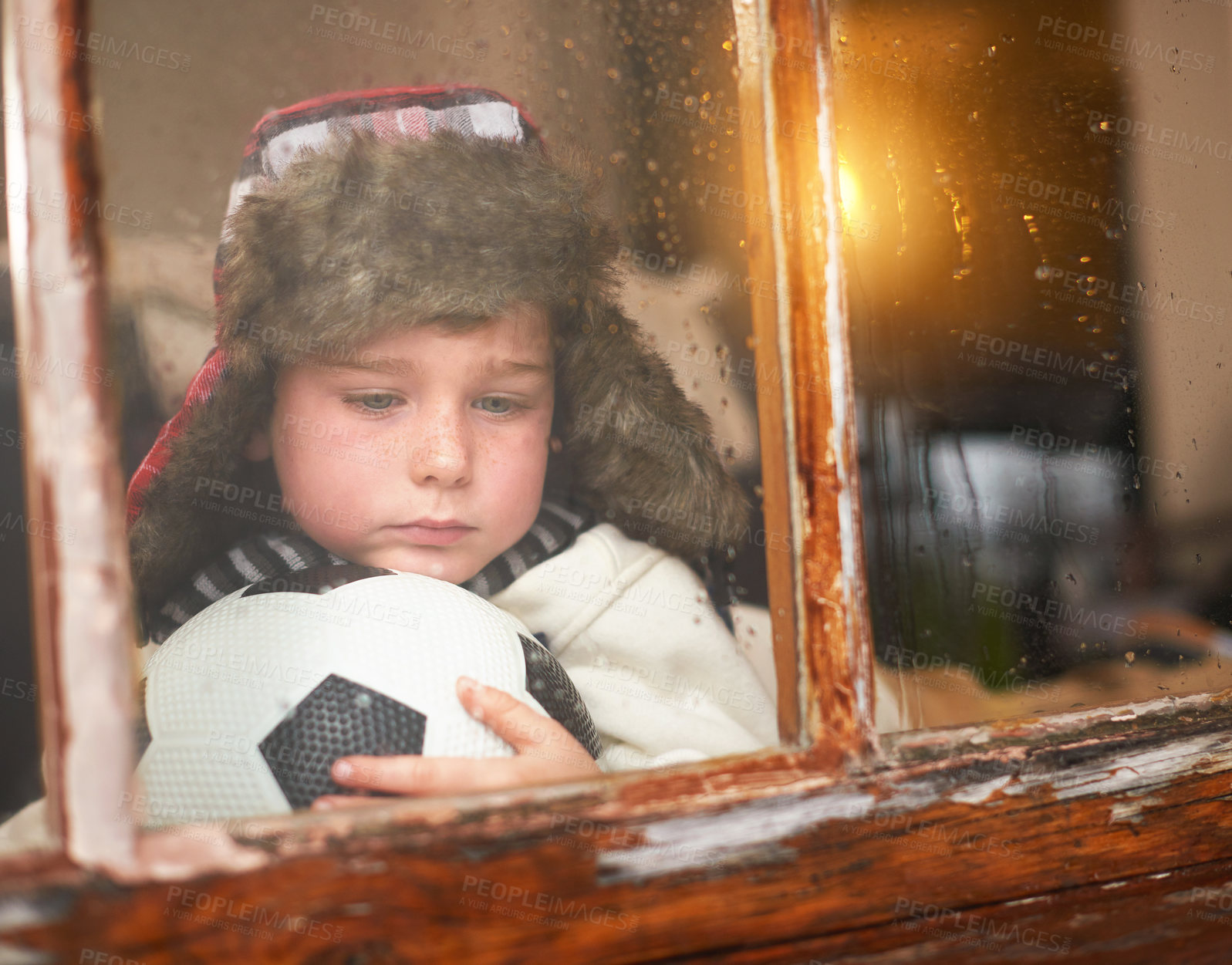 Buy stock photo Thinking, anxiety and depressed child by window for sad with bullying trauma, soccer ball and scared with stress. Orphan, football and young boy by glass for lonely and ideas for adoption in Ireland