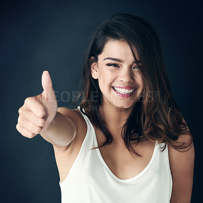 Buy stock photo Studio shot of a beautiful young showing thumbs up against a dark background