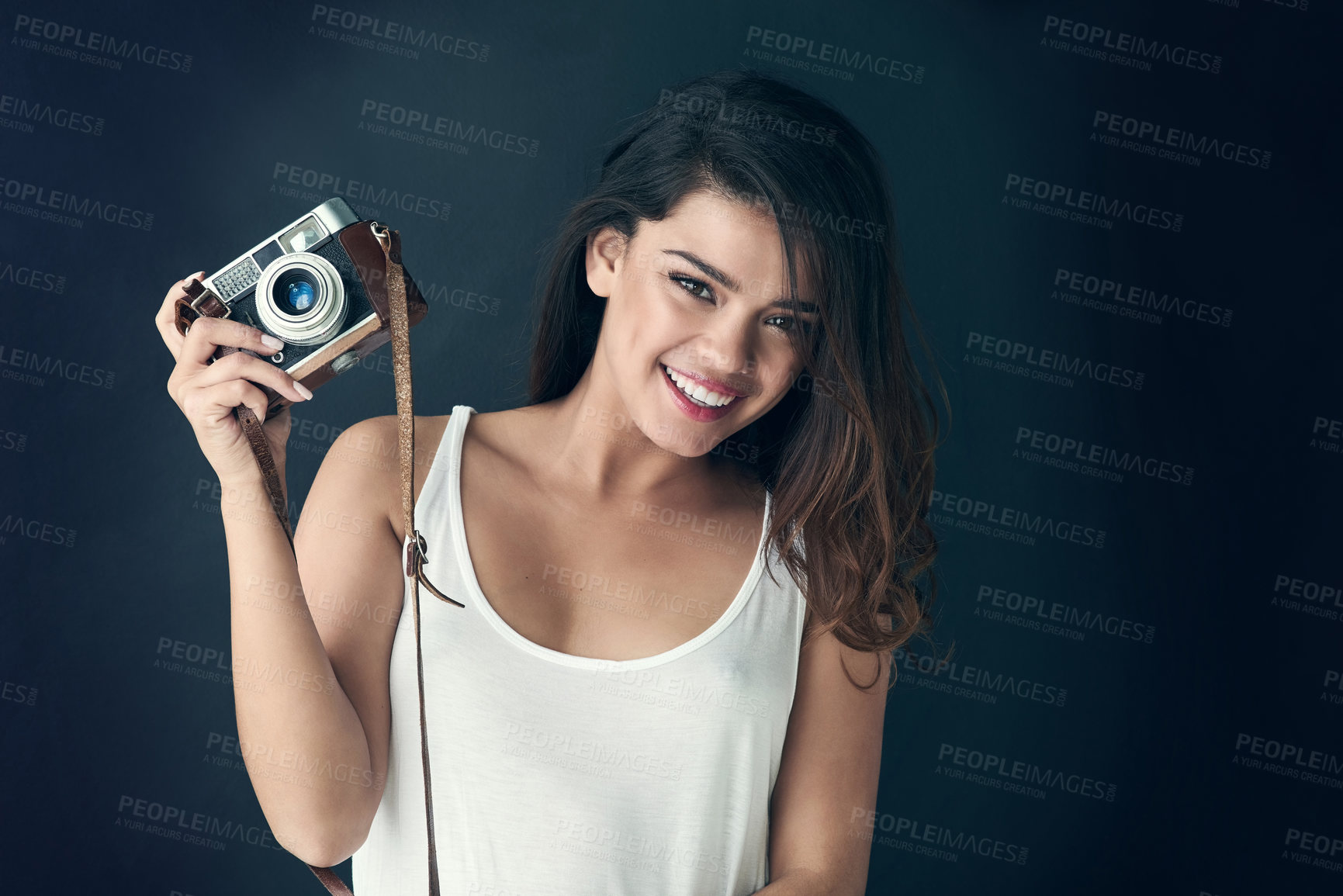 Buy stock photo Cropped shot of a beautiful young holding a camera against a dark background