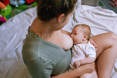 Buy stock photo High angle shot of a young mother breastfeeding her newborn baby at home