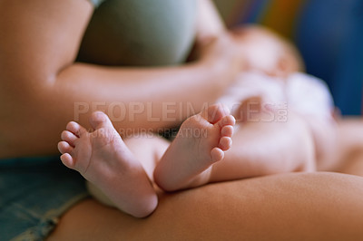 Buy stock photo Closeup shot of a baby’s feet as he lies in his mother’s lap
