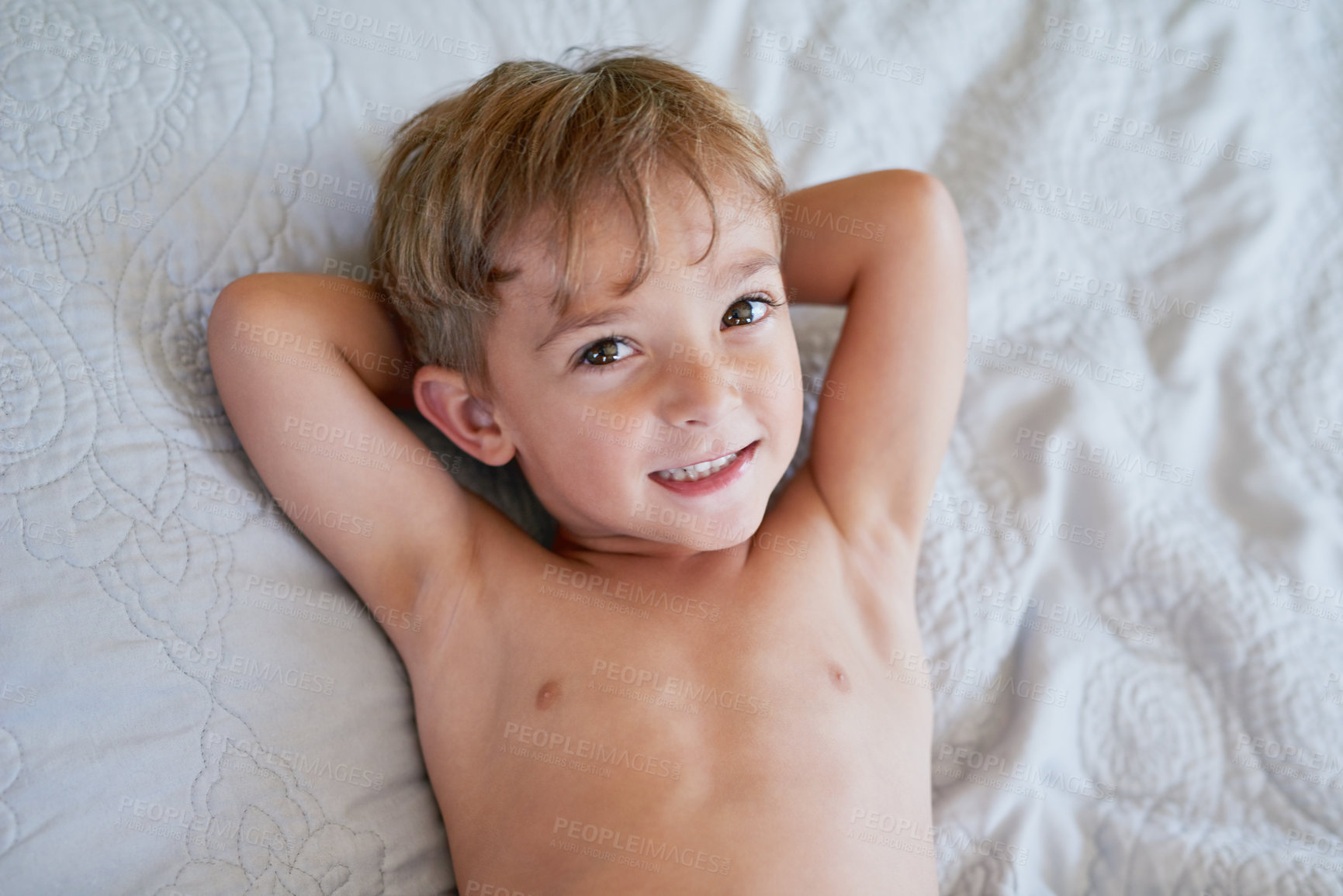 Buy stock photo High angle shot of a young boy lying on a bed with his hands behind his back