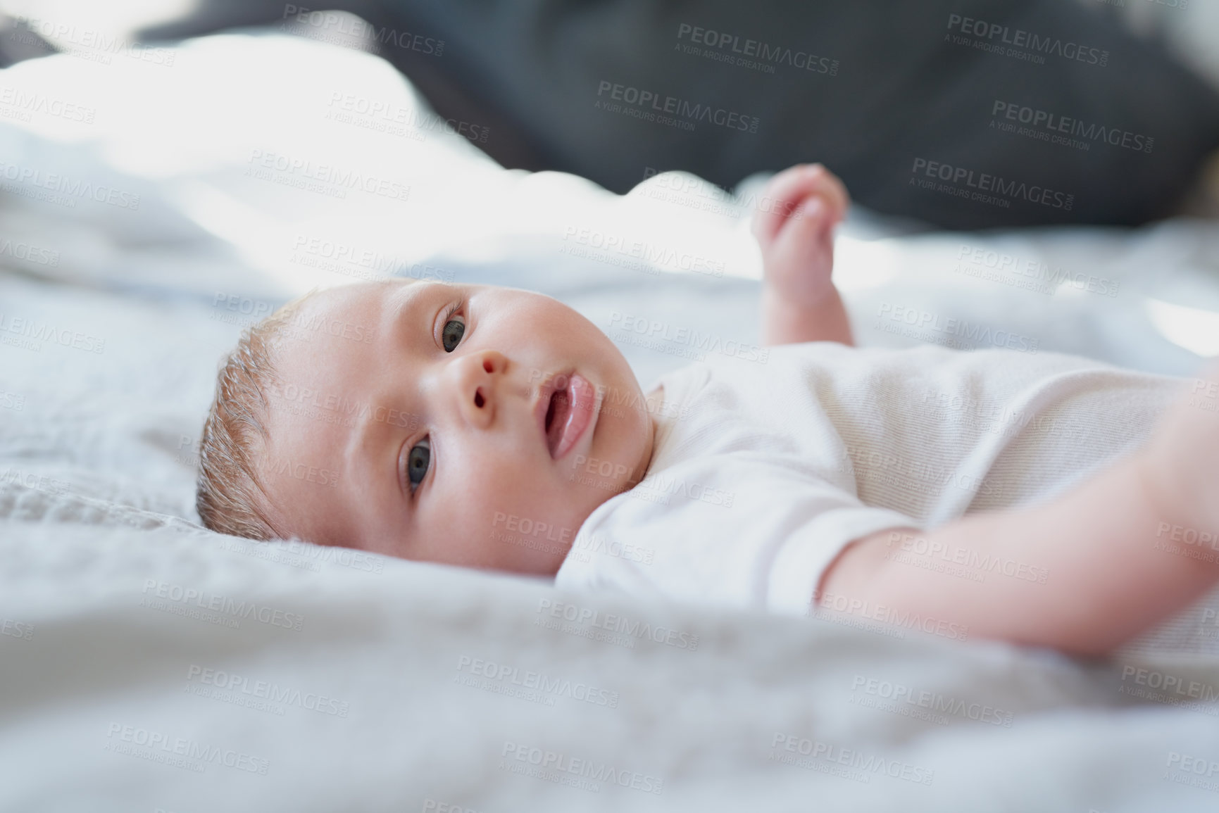 Buy stock photo Shot of an adorable baby boy lying down on a bed at home