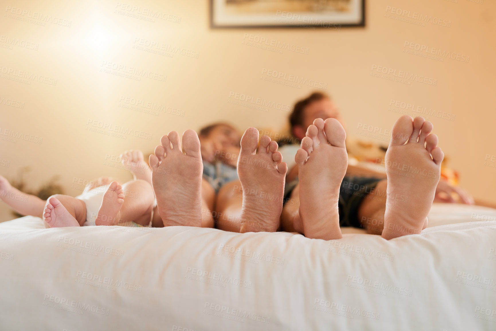 Buy stock photo Shot of a mother, father and their baby’s feet as they relax on the bed at home