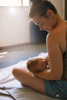 Buy stock photo Shot of a young mother breastfeeding her newborn baby at home