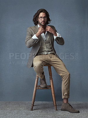 Buy stock photo Full length studio portrait of a handsome and stylish young man sitting on a stool against a grey background