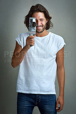 Buy stock photo Studio portrait of a young man posing with a vintage camera against a grey background