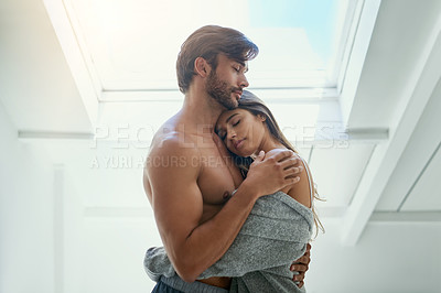 Buy stock photo Shot of an affectionate young couple in a loving embrace at home