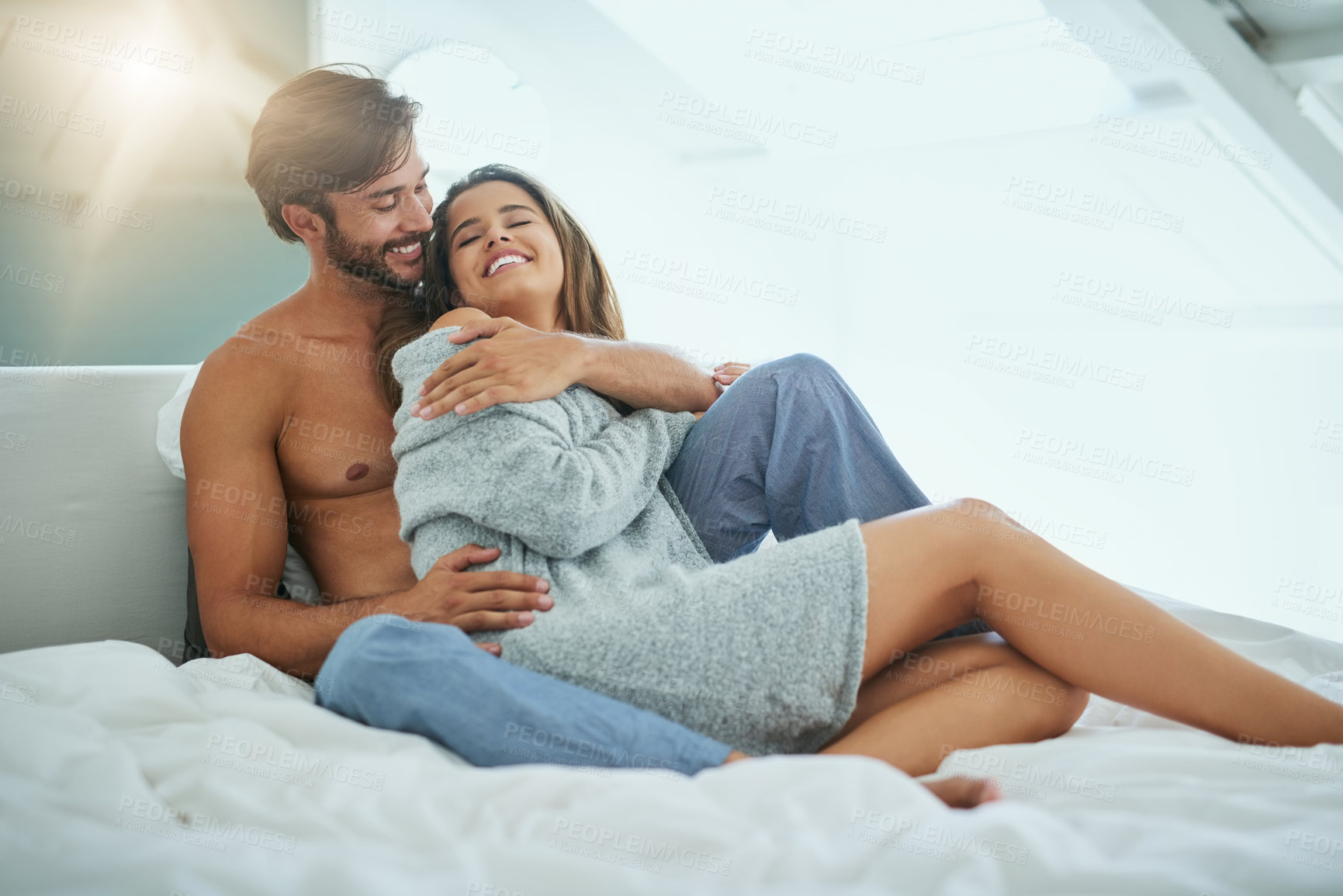 Buy stock photo Shot of an affectionate young couple sharing an intimate moment in bed
