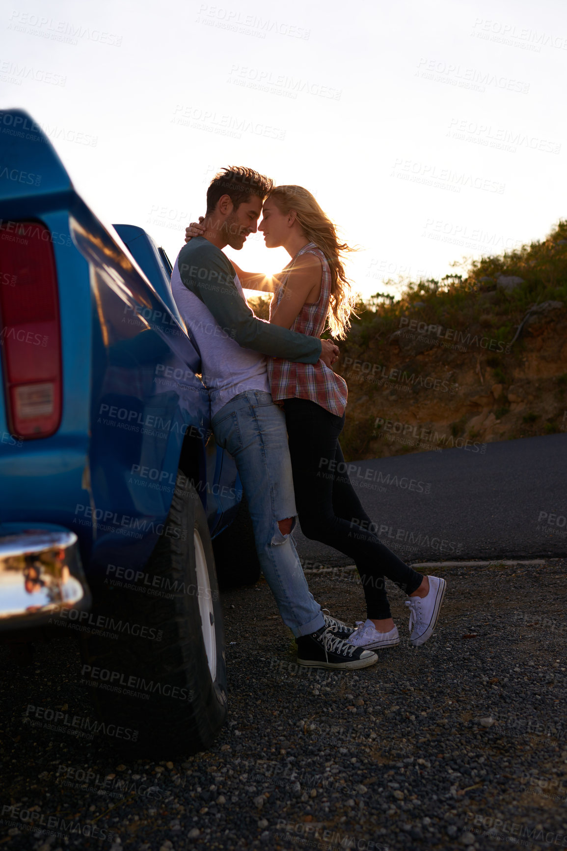 Buy stock photo Shot of an affectionate young couple enjoying a roadtrip together