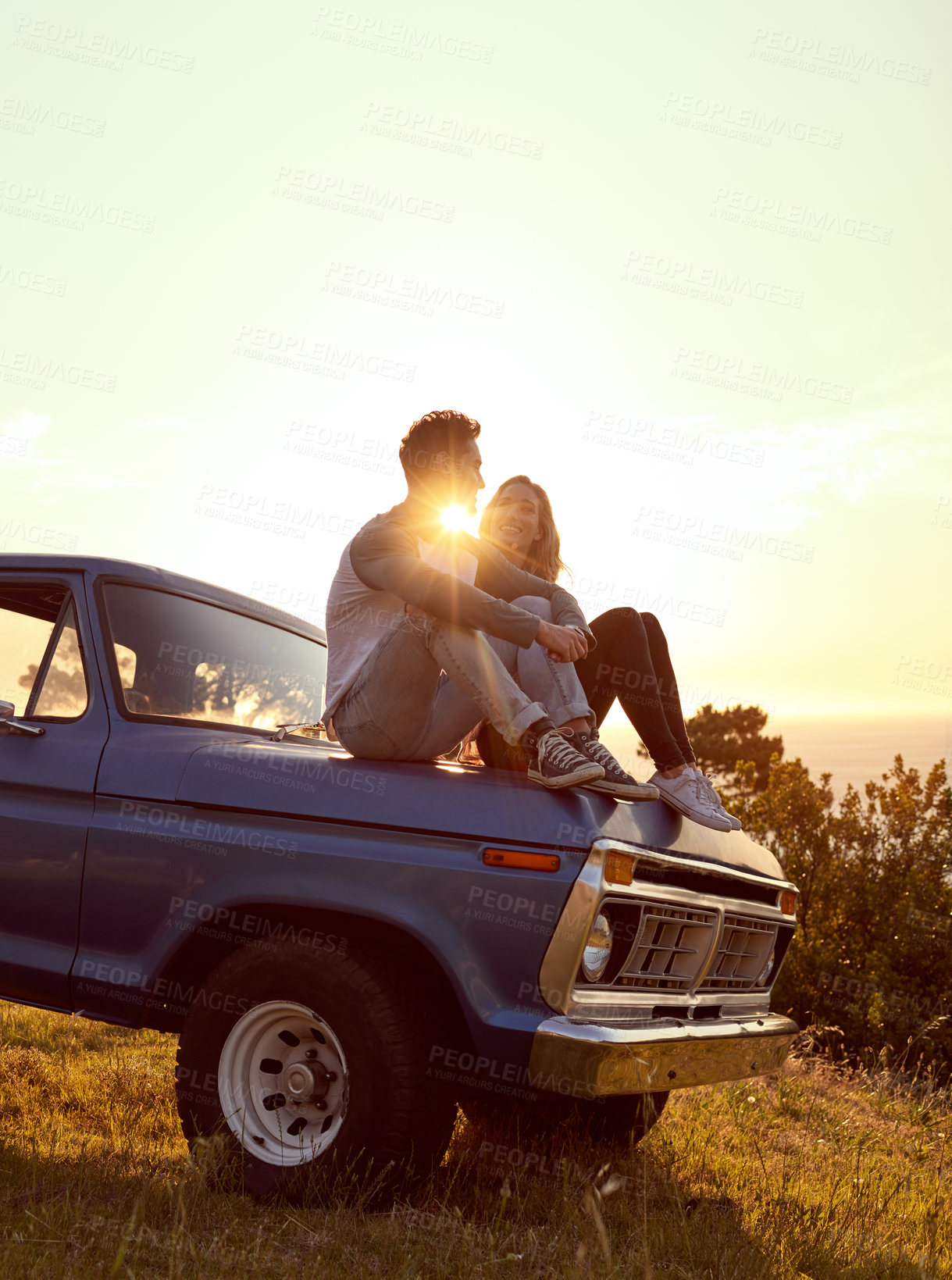 Buy stock photo Love, sunset and couple relax on car for road trip break, travel adventure and sightseeing together. Lens flare, happy people and view of nature for romance, weekend vacation and exploring on mockup