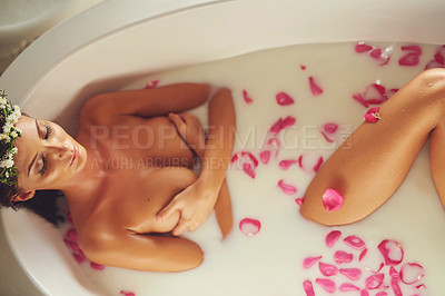 Buy stock photo Portrait of a beautiful nude woman relaxing in a bathtub filled with milk and flower petals at home