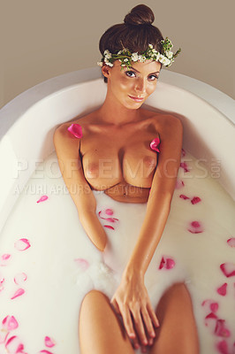 Buy stock photo Portrait of a beautiful nude woman relaxing in a bathtub filled with milk and flower petals at home