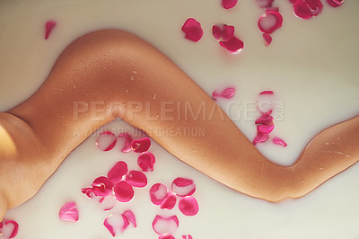 Buy stock photo Cropped shot of an unidentifiable nude woman relaxing in a bathtub filled with milk and rose petals at home