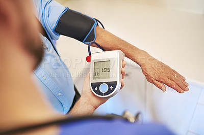 Buy stock photo Shot of an unidentifiable young doctor measuring his senior patient's blood pressure