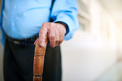 Buy stock photo Shot of an unidentifiable senior man holding a cane while walking down a hallway