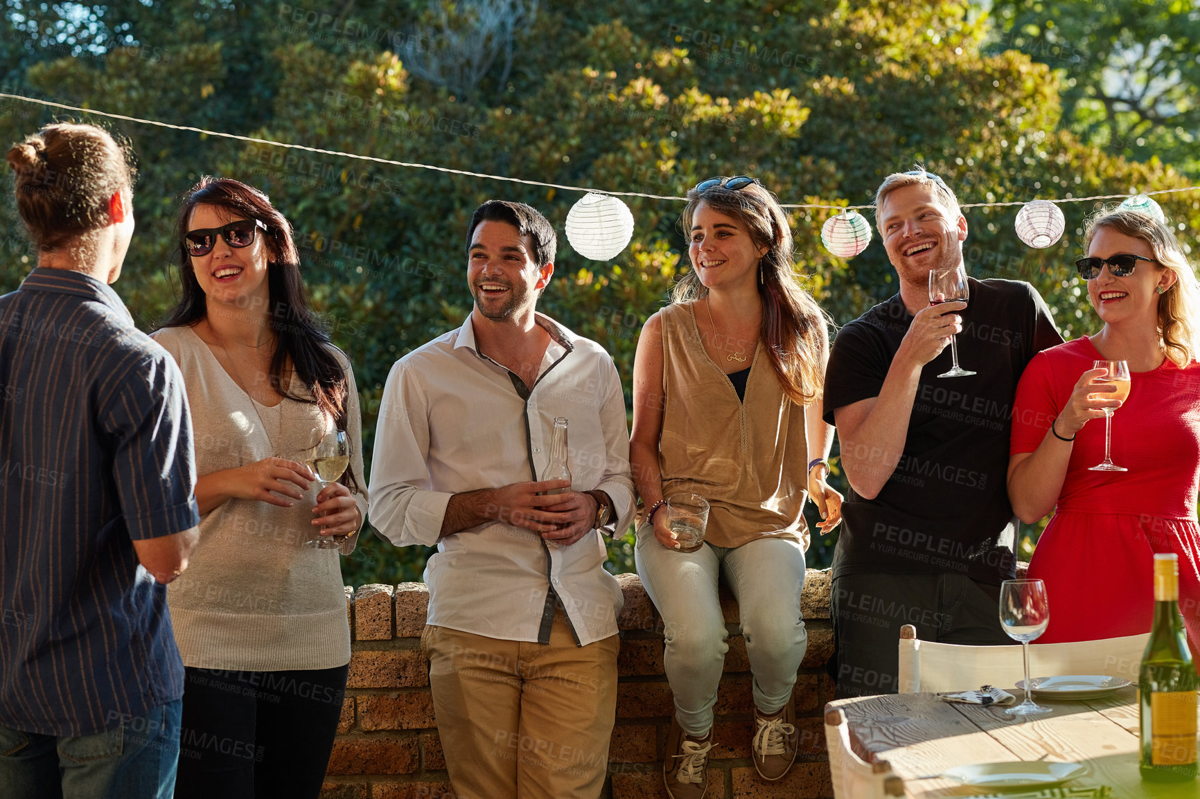 Buy stock photo Shot of a group of happy young friends hanging out at a backyard dinner party