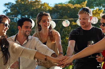 Buy stock photo Shot of a group of happy young friends putting their hands in a pile at an outdoor party