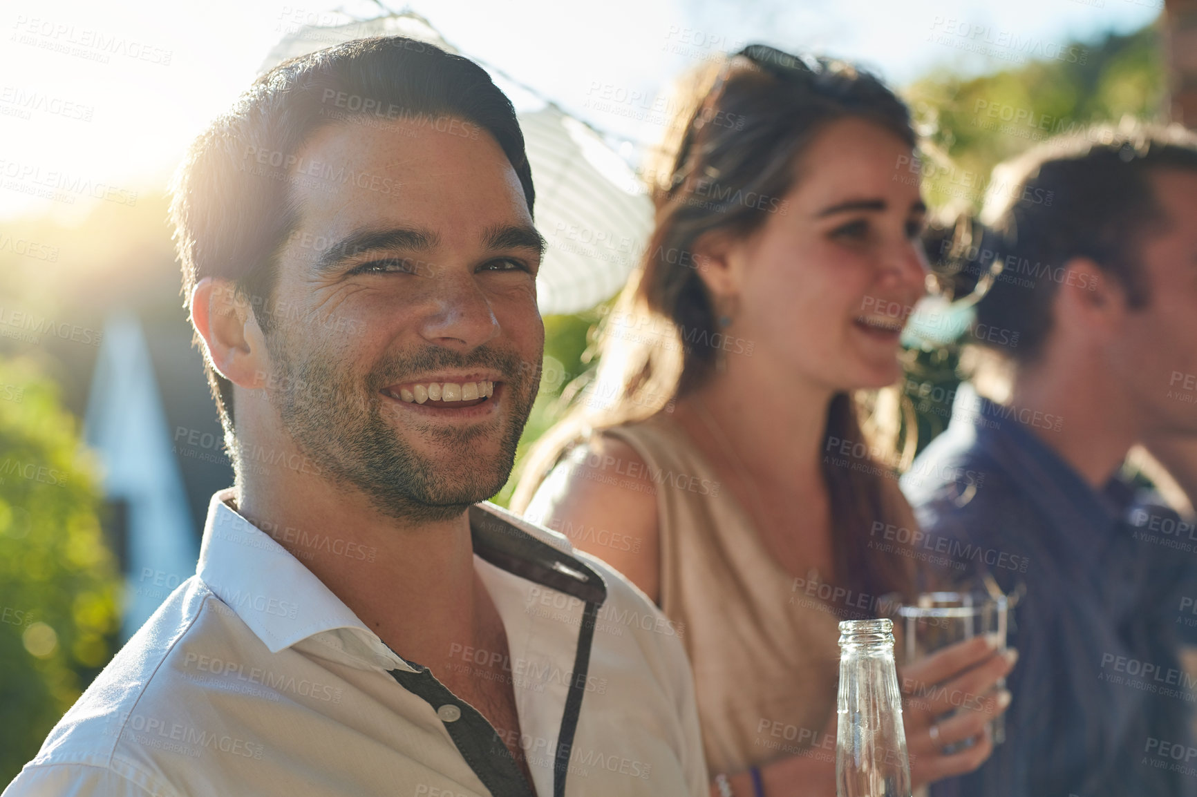 Buy stock photo Portrait of a happy young man spending time with his friends at an outdoor party