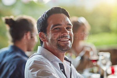Buy stock photo Portrait of a happy young man sharing a meal with friends at an outdoor dinner party