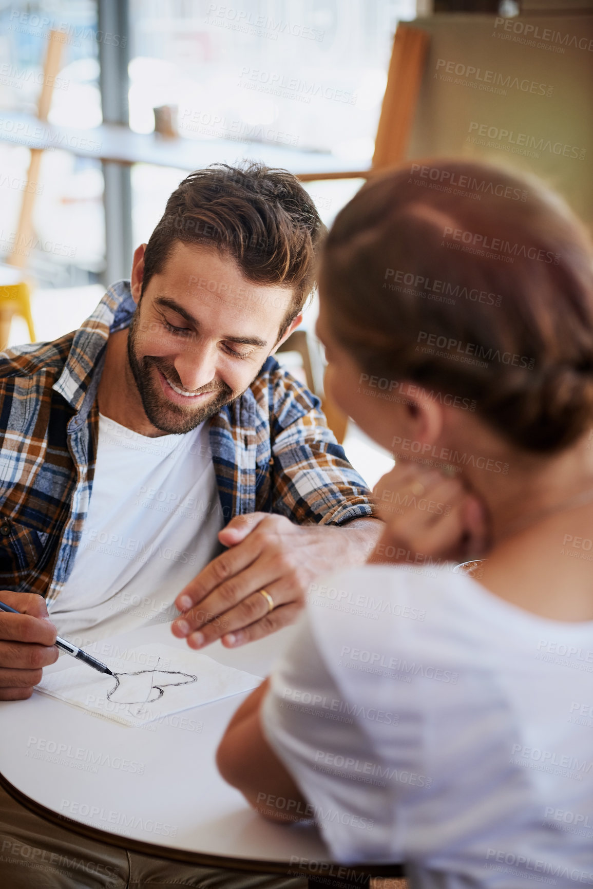 Buy stock photo Happiness, couple and love in cafe for date, commitment and bonding together with smile in relationship. Coffee shop, woman and men with napkin for flirting, heart sketch and romantic in marriage