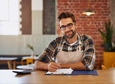 Buy stock photo Portrait of a happy young business owner doing admin at a table in his coffee shop