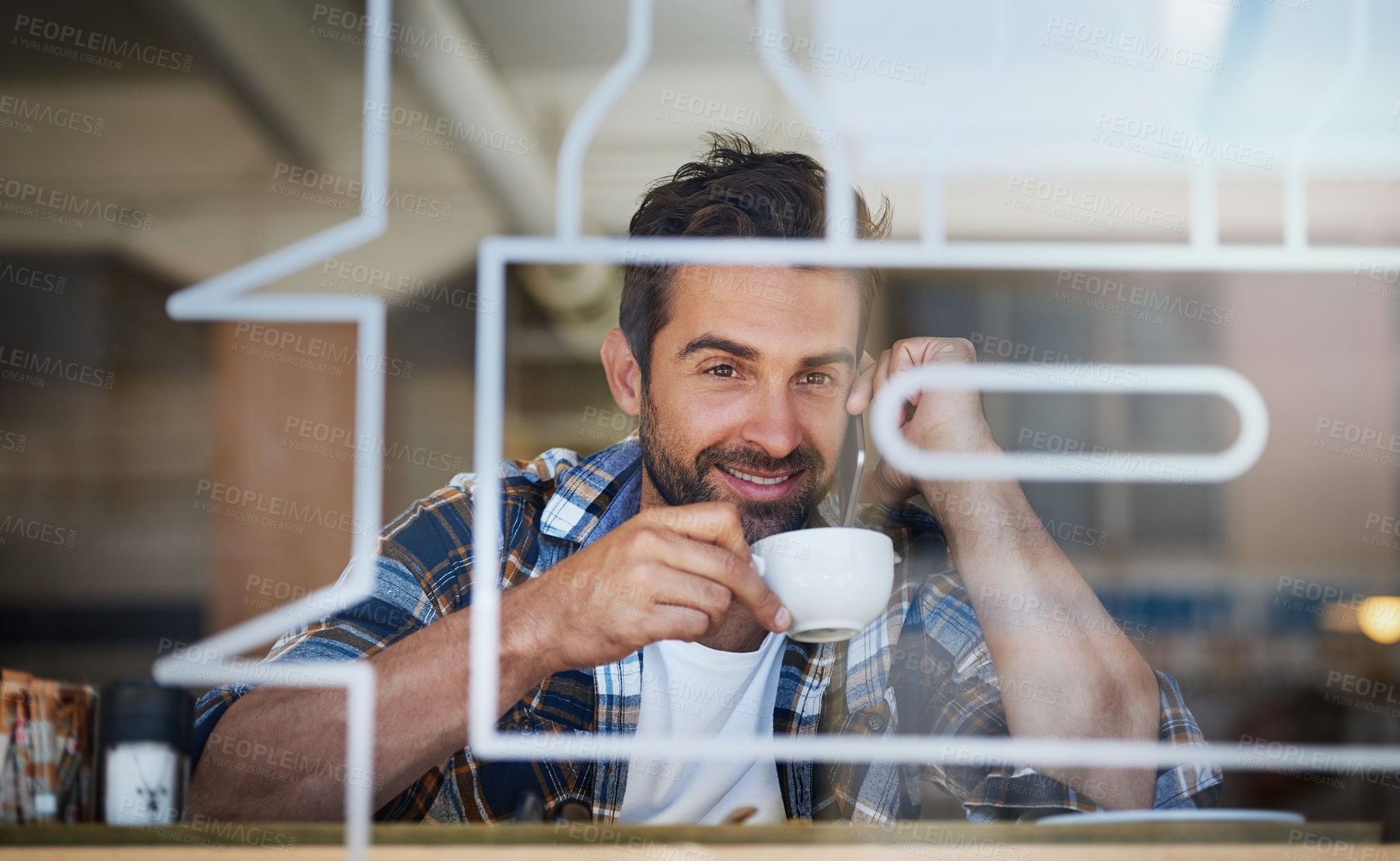 Buy stock photo Portrait of a happy young man answering his cellphone while having coffee at his favorite cafe